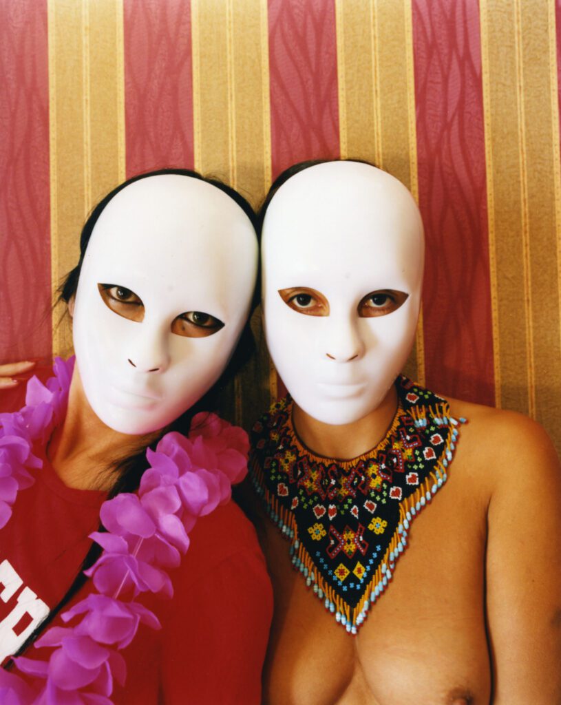 Karen Paulina Biswell y Aicanon fotografía de dos mujeres con máscaras y con los senos 
