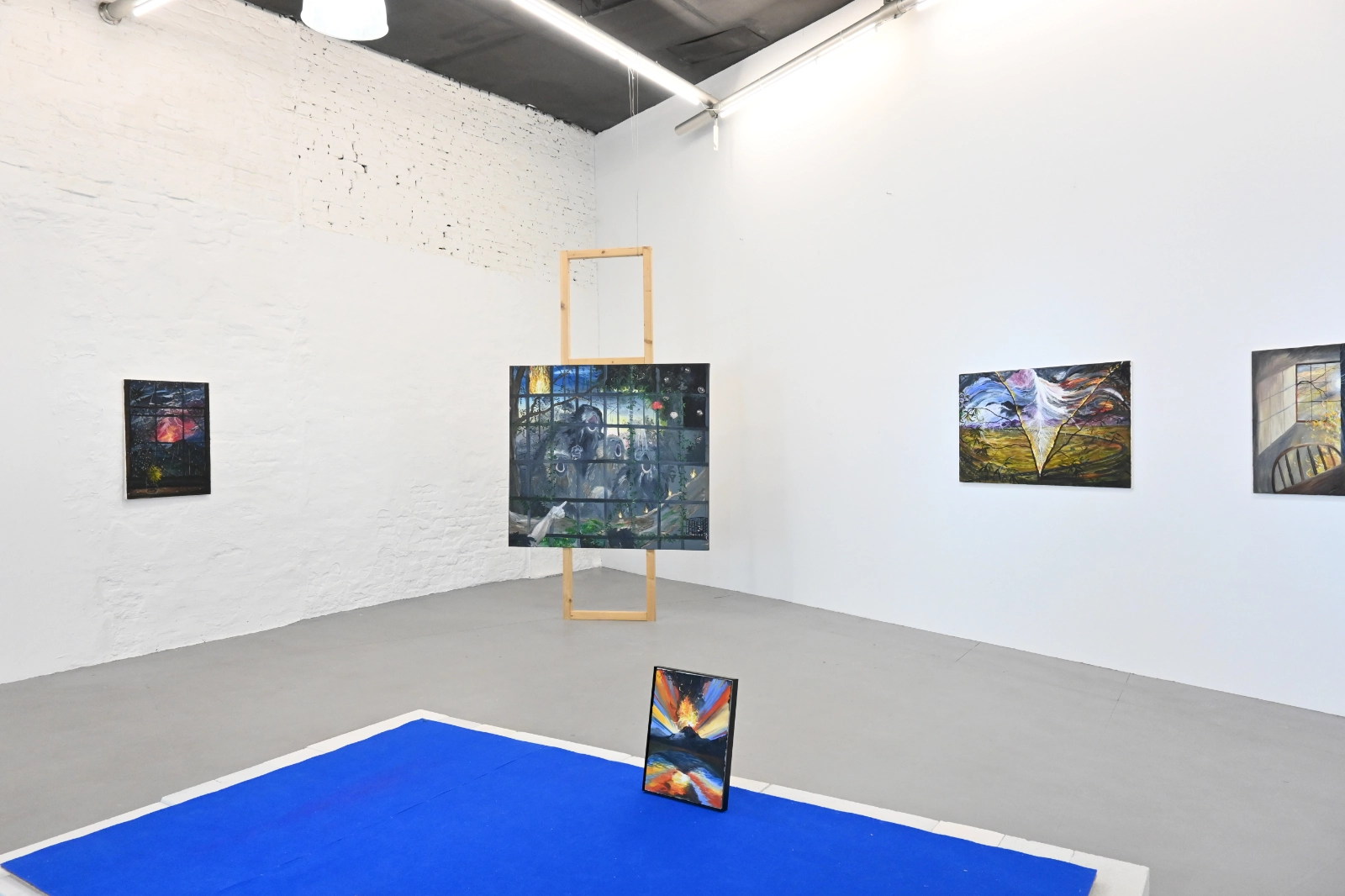 Installation view of Morgan Mandalay’s volcanic paintings and blue floor work at wildpalms