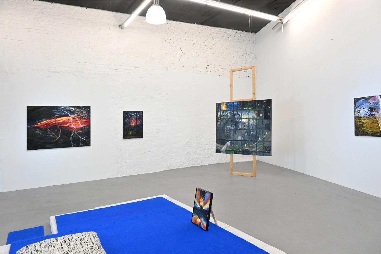 Exhibition view with lightning paintings and blue floor installation in Eruption at Its Peak