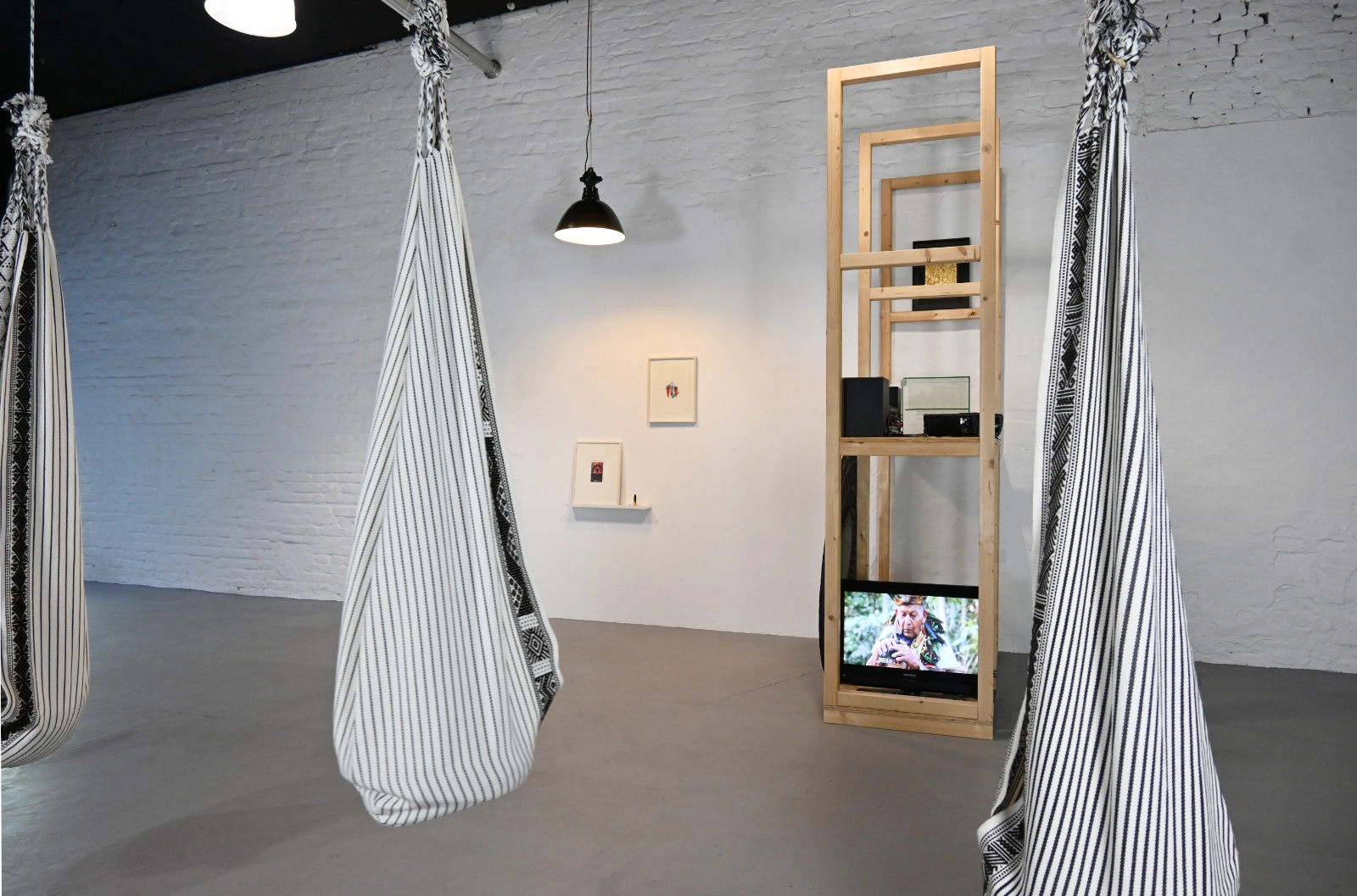 Magical Operations exhibition view with woven hanging seats, video installation and framed works at wildpalms