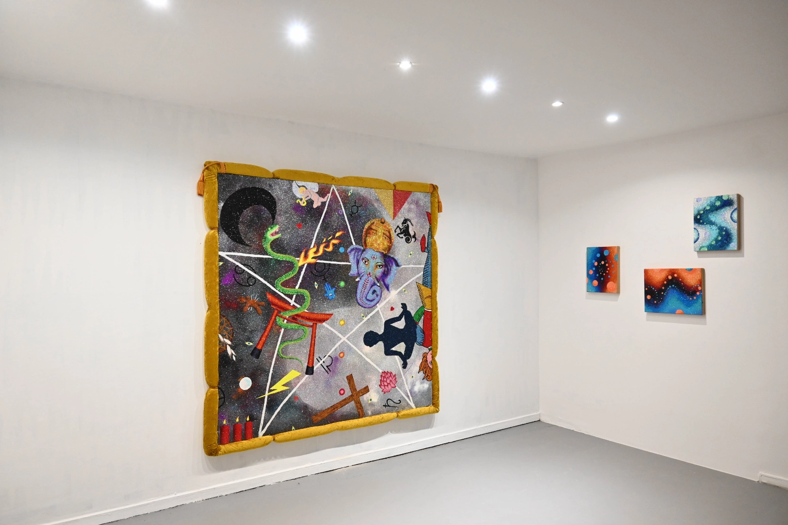 Magical Operations gallery view with a large symbolic textile work and small abstract paintings