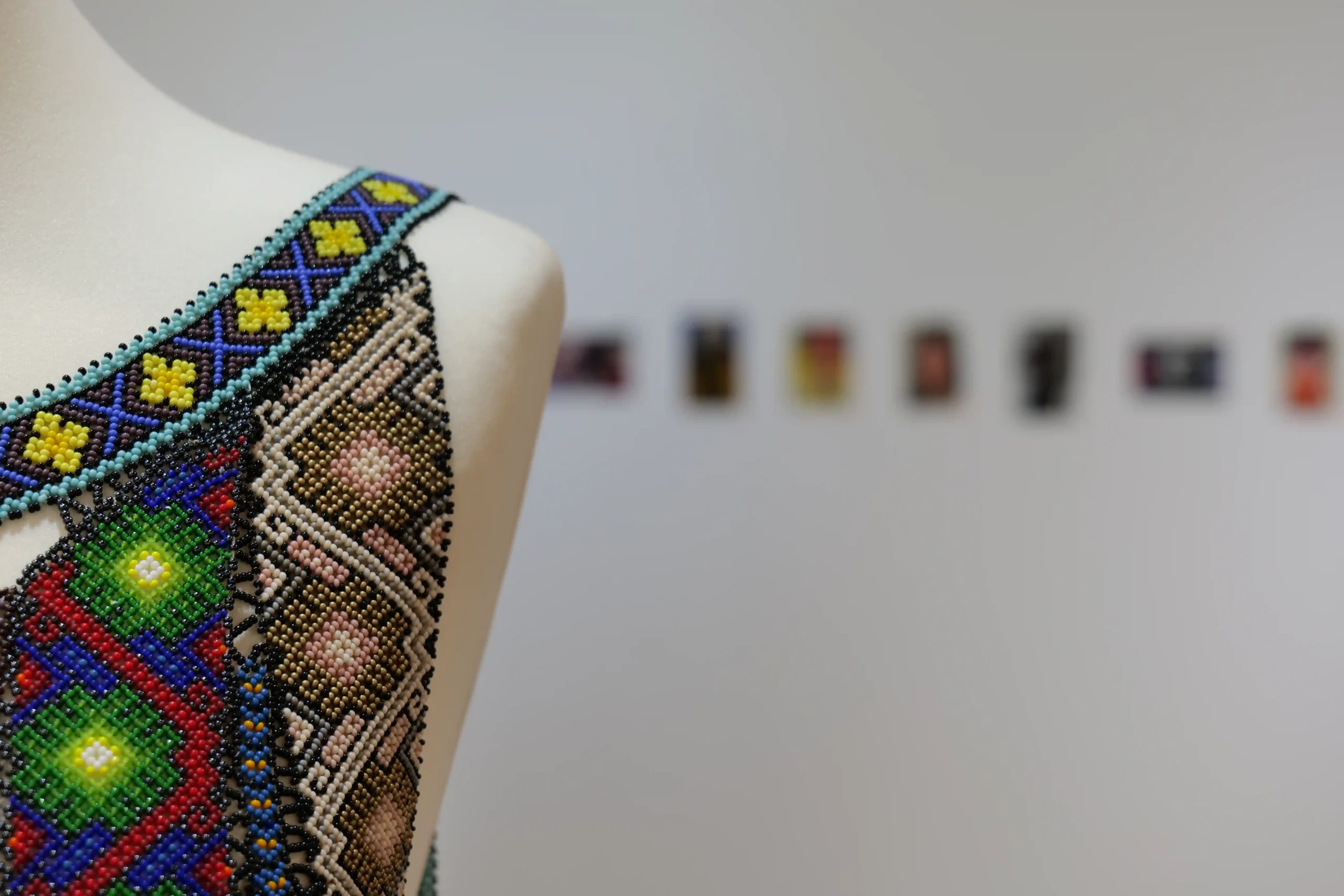 Detail view of a beaded garment in To Produce the Sound of Falling Stones