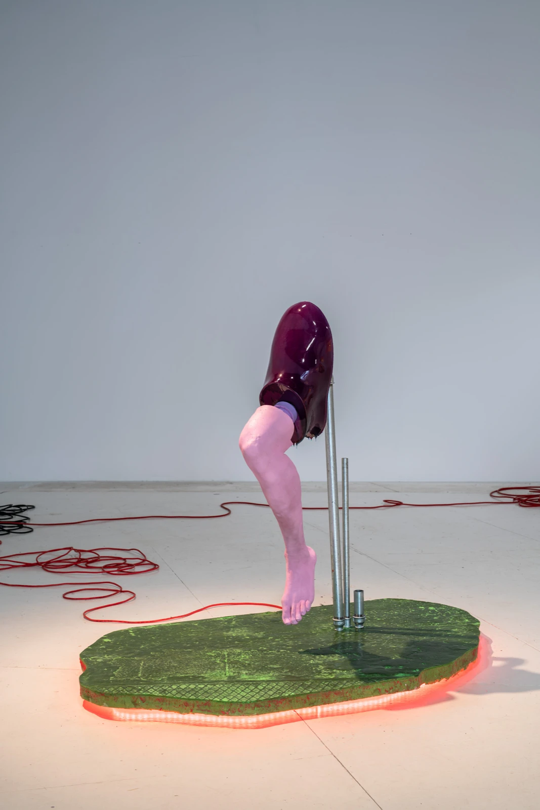 Detalle de la escultura de Malte Bruns — una pierna de maniquí y una forma púrpura brillante sobre un tubo metálico — en Motherboard en wildpalms, Düsseldorf.