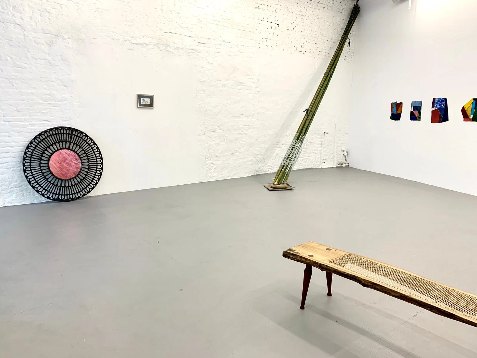 Installation view with stained glass works by Paul Hance and a wood bench by Robert Elfgen, Passage exhibition at wildpalms Düsseldorf, curated by Jorge Sanguino